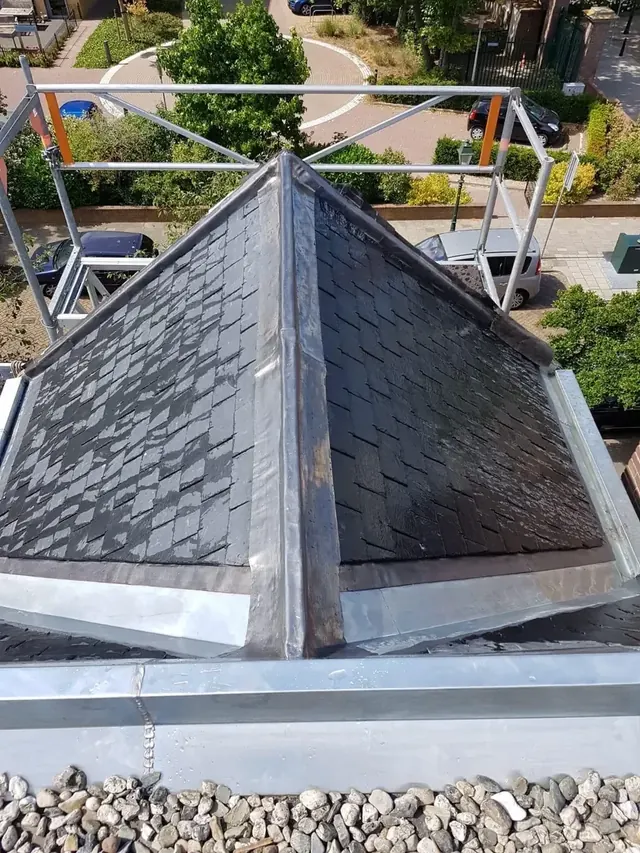 Leien dakopbouw van opzij — Een dakopbouw met leien bekleding en metalen randafwerking.